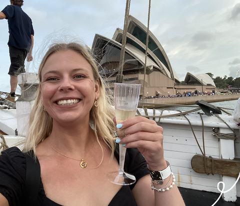 Women with a glass of champagne in front of the Sydney opera house