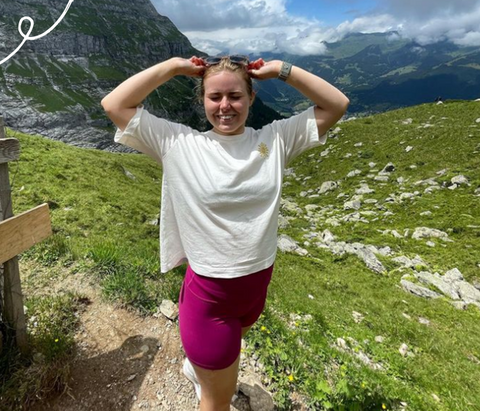 Girl hiking and smiling with sunglasses on her head