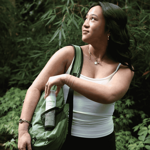 Woman holding a green bottle with a forest background